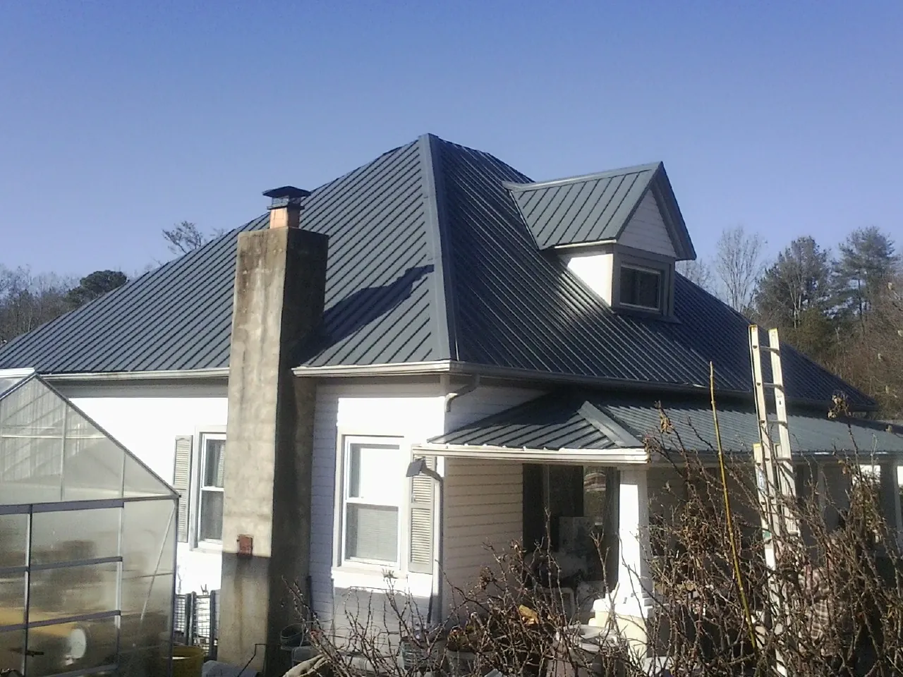 Dark blue standing seam metal roof on a white farmhouse with dormer — Slate & Tile Roof Repair by Roofing Brothers in Bantam