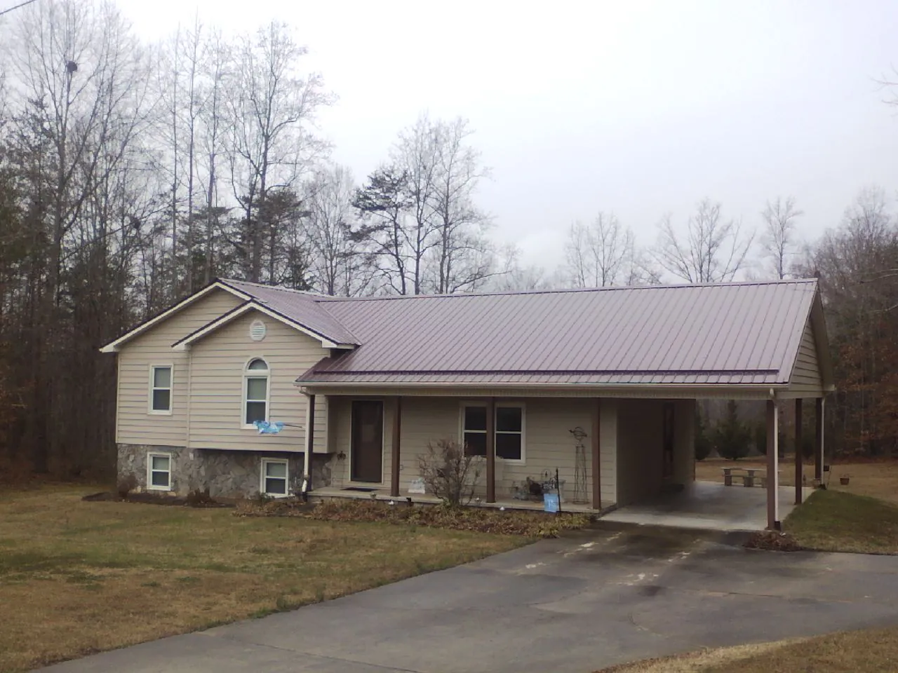 Burgundy metal roof on a tan split level home with an attached carport in Bantam