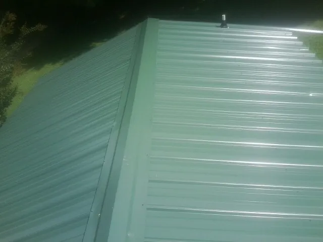 New green metal panels meeting at the ridge of a roof — Flat Roof Repair work by our crew in Bantam