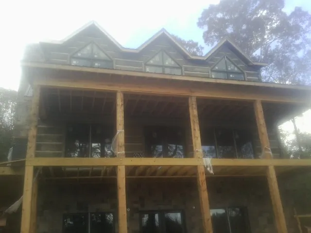 Dormers and porch framing on a large log home under construction — Roof Coating work by our crew in Bantam