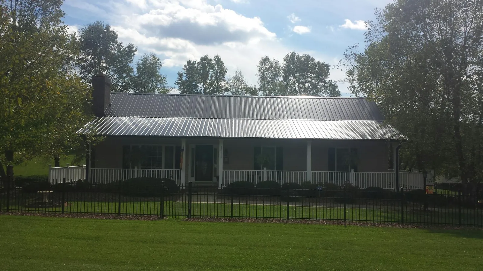 Gray metal roof on a brick ranch with a full width front porch — Gutter Guard Installation work by our crew in Bantam